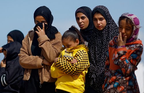 People bury the bodies of Palestinians killed in Israeli strikes and fire, at a mass grave in Rafah