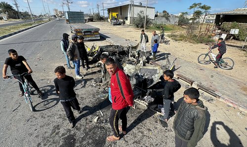 Palestinians inspect the site of an Israeli strike on a car, in Rafah