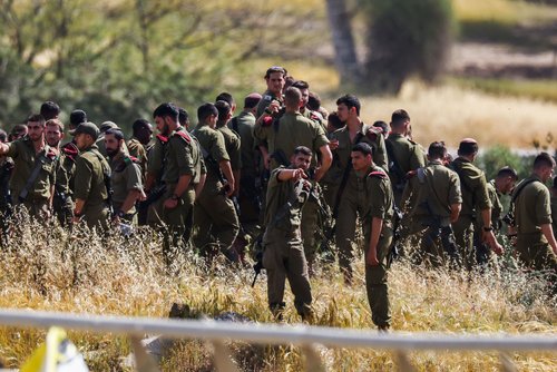 Israeli soldiers gather by the side of a road, in Israel