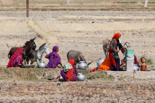 Women gather for washing and to fetch water at a handpump during a hot summer day on the outskirts of Larkana