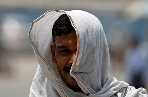FILE PHOTO: A man covers himself with a cloth to protect from heat on a hot summer day