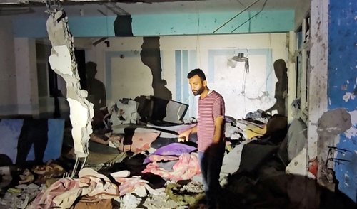 Palestinians inspect the site of an Israeli strike on a school sheltering displaced people in Nuseirat refugee camp in the central Gaza Strip