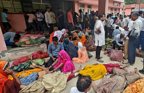 People mourn next to the bodies of victims of a stampede outside a hospital in Hathras district