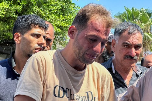 Palestinian father mourns twins killed in an Israeli strike while bringing their birth certificates