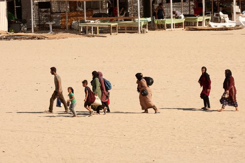 People carry belongings at a beach as they flee, in Tyre