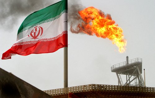 FILE PHOTO: A gas flare on an oil production platform is seen alongside an Iranian flag in the Gulf