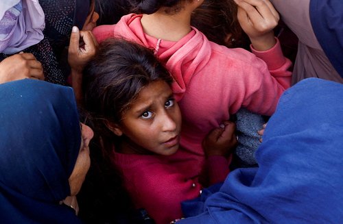 Palestinians gather to buy bread from a bakery, in Khan Younis