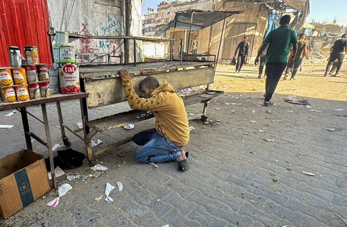 An injured Palestinian kneels on the ground following an Israeli strike, in Beit Lahiya