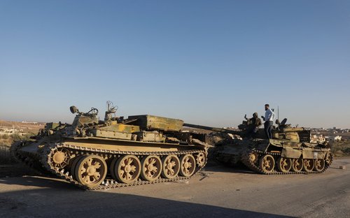 Men stand on a military vehicle in the city of Maarat al-Numan, in Idlib province