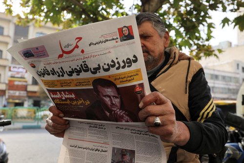 FILE PHOTO: An Iranian man reads a newspaper with a picture of Syrian President Bashar al-Assad in Tehran