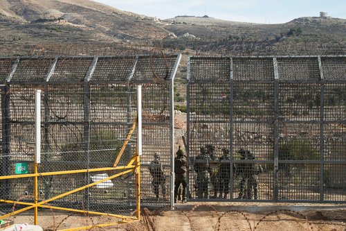 Israeli soldiers syand on the Syrian side of the ceasefire line between Syria and the Israeli-occupied Golan Heights, as seen from the Golan Heights