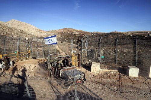 An Israeli military vehicle rides by the ceasefire line between the Israeli-occupied Golan Heights and Syria, as seen from Majdal Shams in the Golan Heights