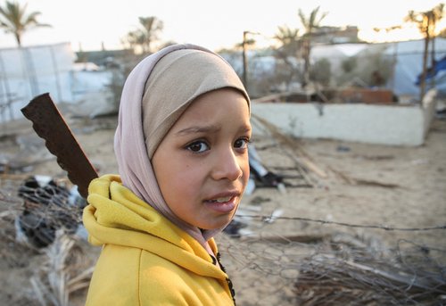Palestinians inspect the damage at a tent camp sheltering displaced people, following an Israeli strike, in Khan Younis