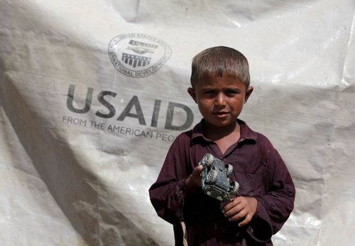 FILE PHOTO: Sajad, 7, who has been displaced by flooding, holds his toy jeep outside his family tent with the weather sheet donated by USAID, near Kari Mori