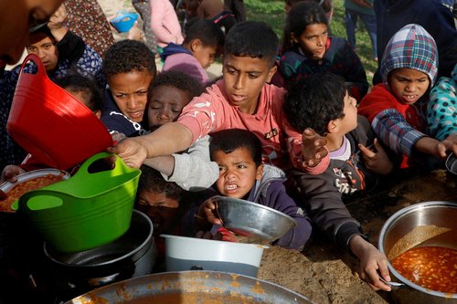 FILE PHOTO: Palestinians gather to receive food cooked by a charity kitchen, in Khan Younis