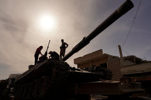 Syrian troops sit atop tank as they head towards the Syrian-Lebanese border following clashes with Lebanese soldiers and armed groups, in Qusayr