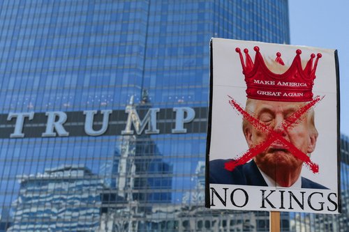 A person holds a sign with an image depicting U.S. President Donald Trump as demonstrators walk past the Trump Tower during a "No Kings" protest