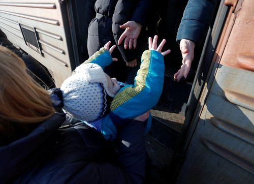 Evacuees board a train at a railway station before leaving Makiivka