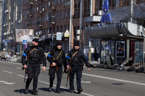 Armed police officers walk past the Artem factory in Kyiv after it was hit by shelling as Russia's attack on Ukraine continues