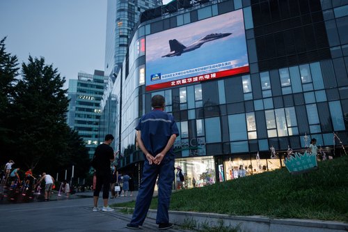 A man watches a news broadcast, showing joint military operations near Taiwan by the Chinese People's Liberation Army's (PLA), in Beijing