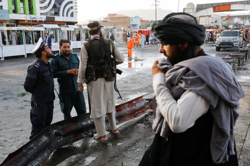 Taliban fighters stand guard at the site of a blast in Kabul