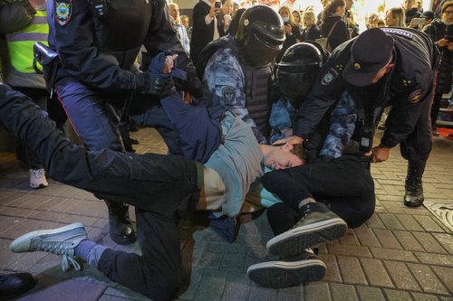 Russian police officers detain men during an unsanctioned rally in Moscow