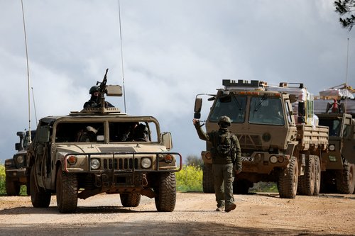 FILE PHOTO: An Israeli soldier gestures while walking next to military vehicles, after Israel forces launched a new campaign against Iran-backed Hezbollah in southern Lebanon