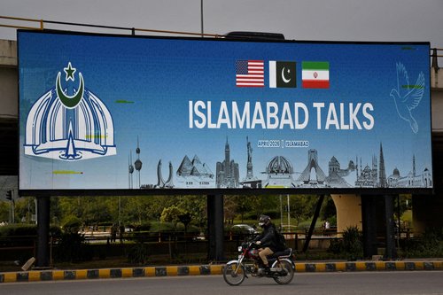 FILE PHOTO: A man rides his motorbike past a billboard installed alongside