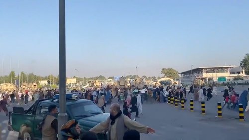A horde of people run towards the Kabul Airport Terminal, after Taliban insurgents took control of the presidential palace in Kabul
