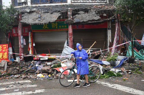 Person pushes a bicycle past collapsed buildings following an earthquake in Luzhou city of southwestern province of Sichuan