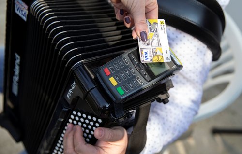 A person pays through using a credit card terminal installed on Zeljko's accordion in front of his home in Banja Luka