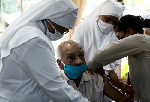 FILE PHOTO: Nuns hold a man as he receives a dose of COVAXIN COVID-19 vaccine at a home for elderly in Mumbai
