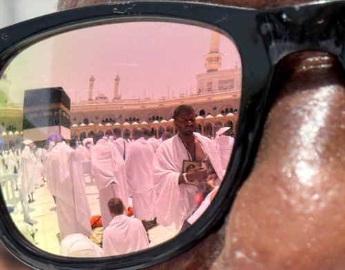 Pilgrims are reflected in sunglasses as they attend Friday