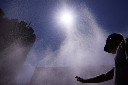 A man cools off in a water spray from a public outdoor sprinkler system to alleviate high temperatures at Rudolfplatz square, amid a heatwave in Cologne, Germany, June 25, 2026. REUTERS/Thilo Schmuelgen