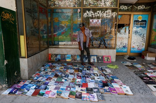 A man offers second-hand books and vinyl records for sale outside a disused state-owned store