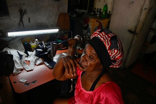 Irma Ribas, 68, who was a pensioner but was rehired at a hospital to work in the sterilization area, sits at her sewing machine at home