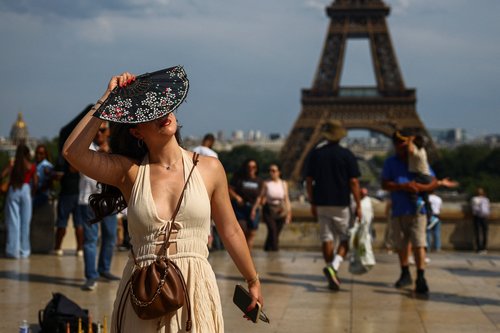 A woman with a hand fan stands on the Trocadero square near the Eiffel Tower as temperatures rise in Paris during a second heatwave affecting a large part of France, June 20, 2026. REUTERS/Sarah Meyssonnier