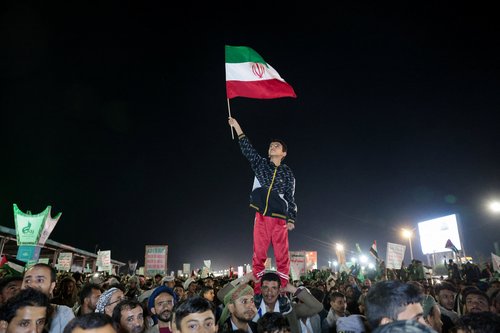 A boy waves an Iranian flag as he joins Houthi