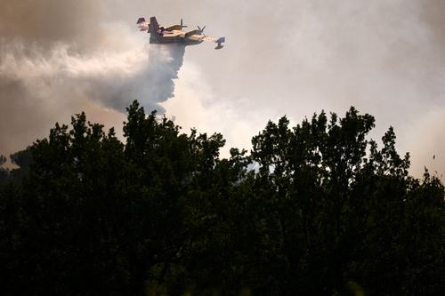 A Canadair firefighting aircraft drops water to battle a wildfire