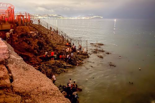 Migrants gather near a fence while waiting for a chance to cross to the Spanish enclave of Ceuta, on the Moroccan side of the border in Fnideq, Morocco, July 31, 2026. Picture taken with a mobile phone. REUTERS/Stringer