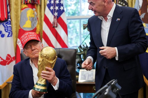 FILE PHOTO: U.S. President Donald Trump holds the FIFA World Cup Trophy, as he makes an announcement on the 2026 FIFA World Cup, as FIFA president Gianni Infantino stands next to him, in the Oval Office at the White House in Washington, D.C., U.S., August