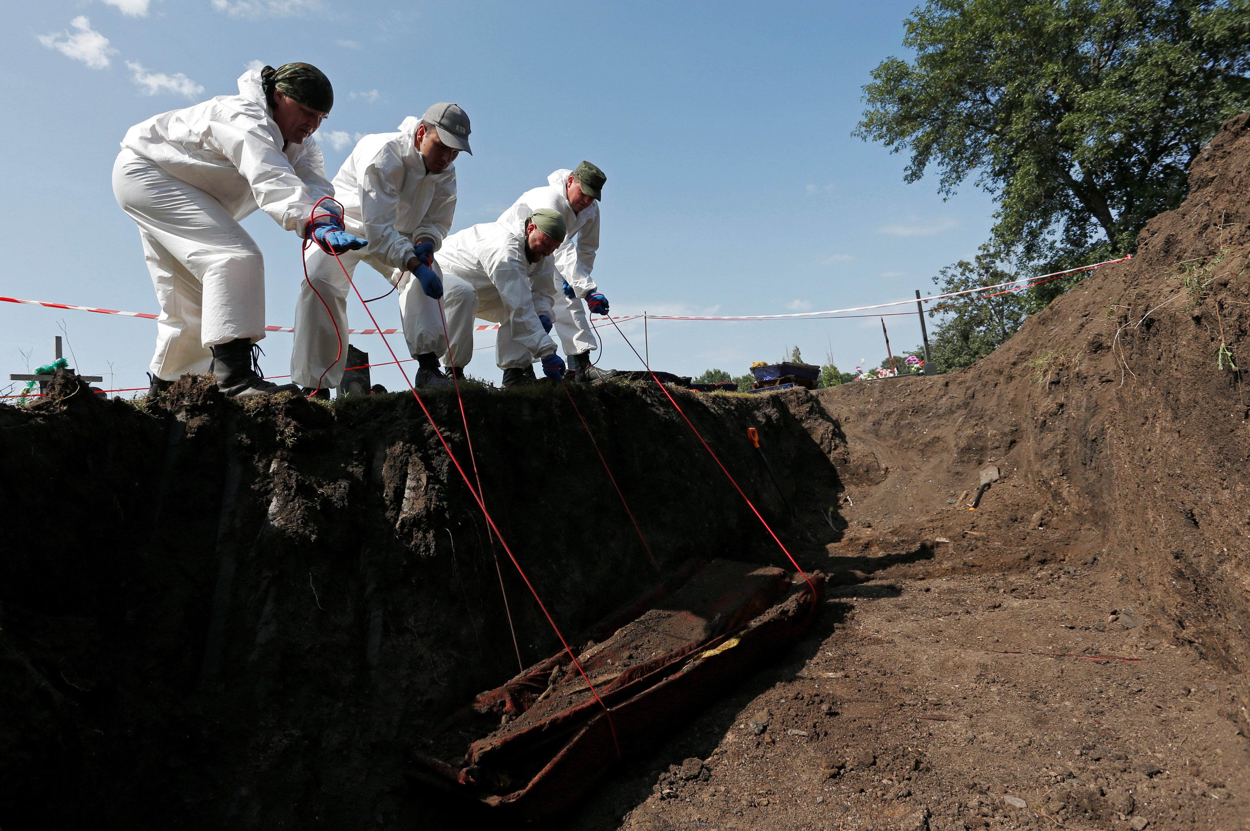 Volunteers take part in the exhumation of remains of people killed during the military conflict in eastern Ukraine, in Snizhne