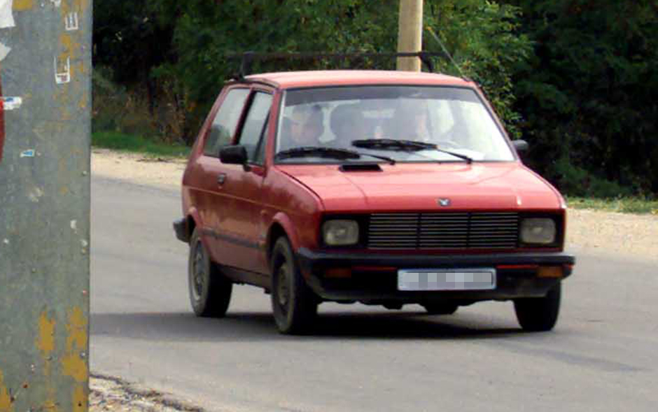 A YUGO CAR PASSES SERBIAN GRAFFITI IN GRACANITA VILLAGE IN KOSOVO.