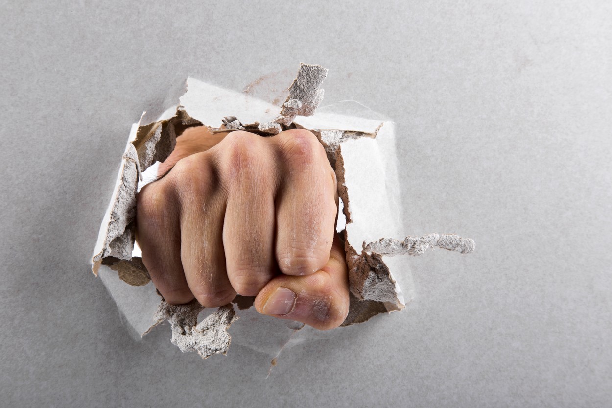 aggression concept, wall is broken through by a fist