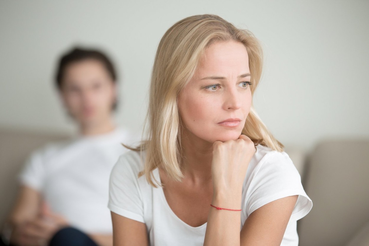 Serious sad woman thinking over a problem, man sitting aside