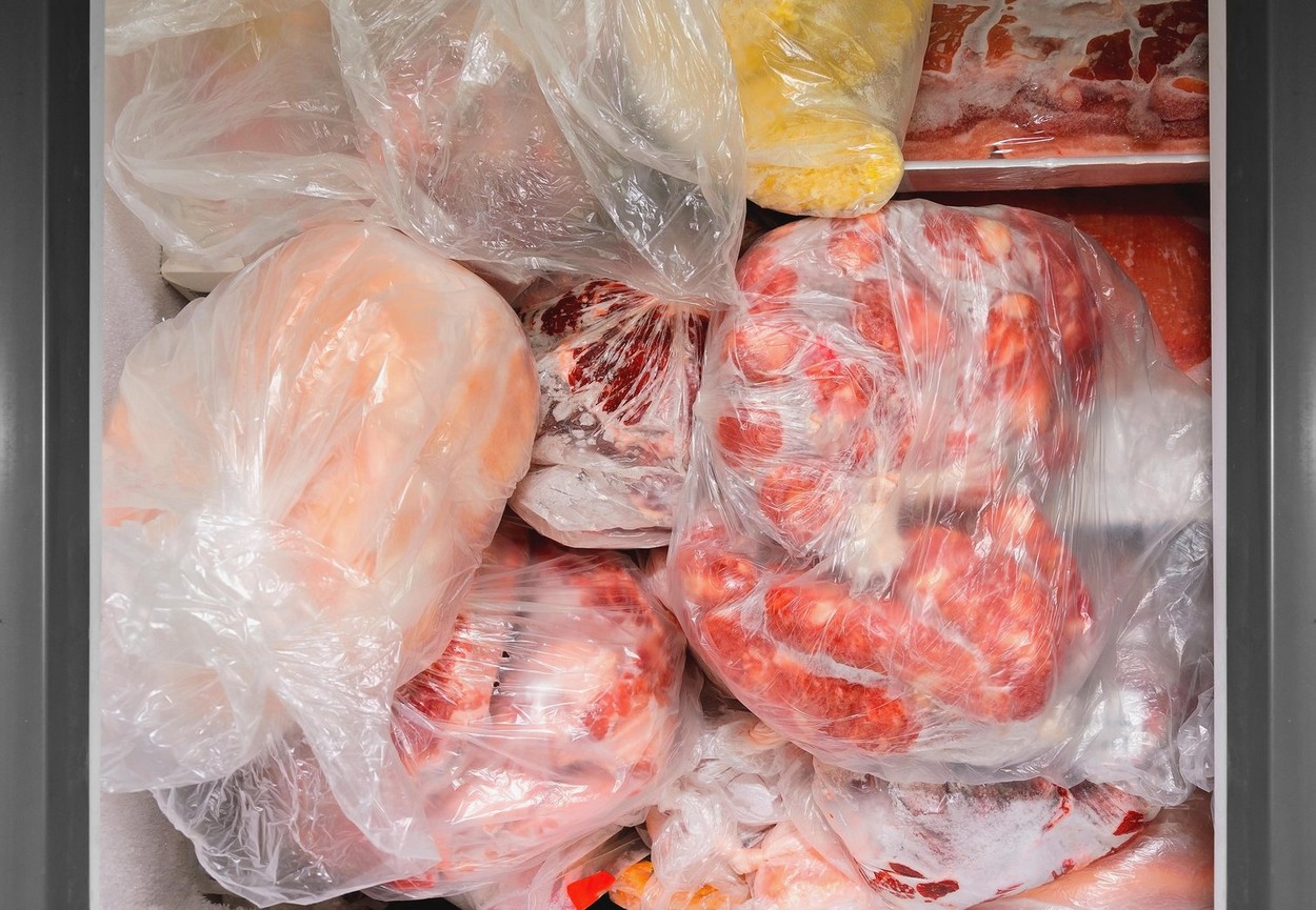 Frozen food in the freezer. Bagged frozen meat in a horizontal freezer. Food preservation.