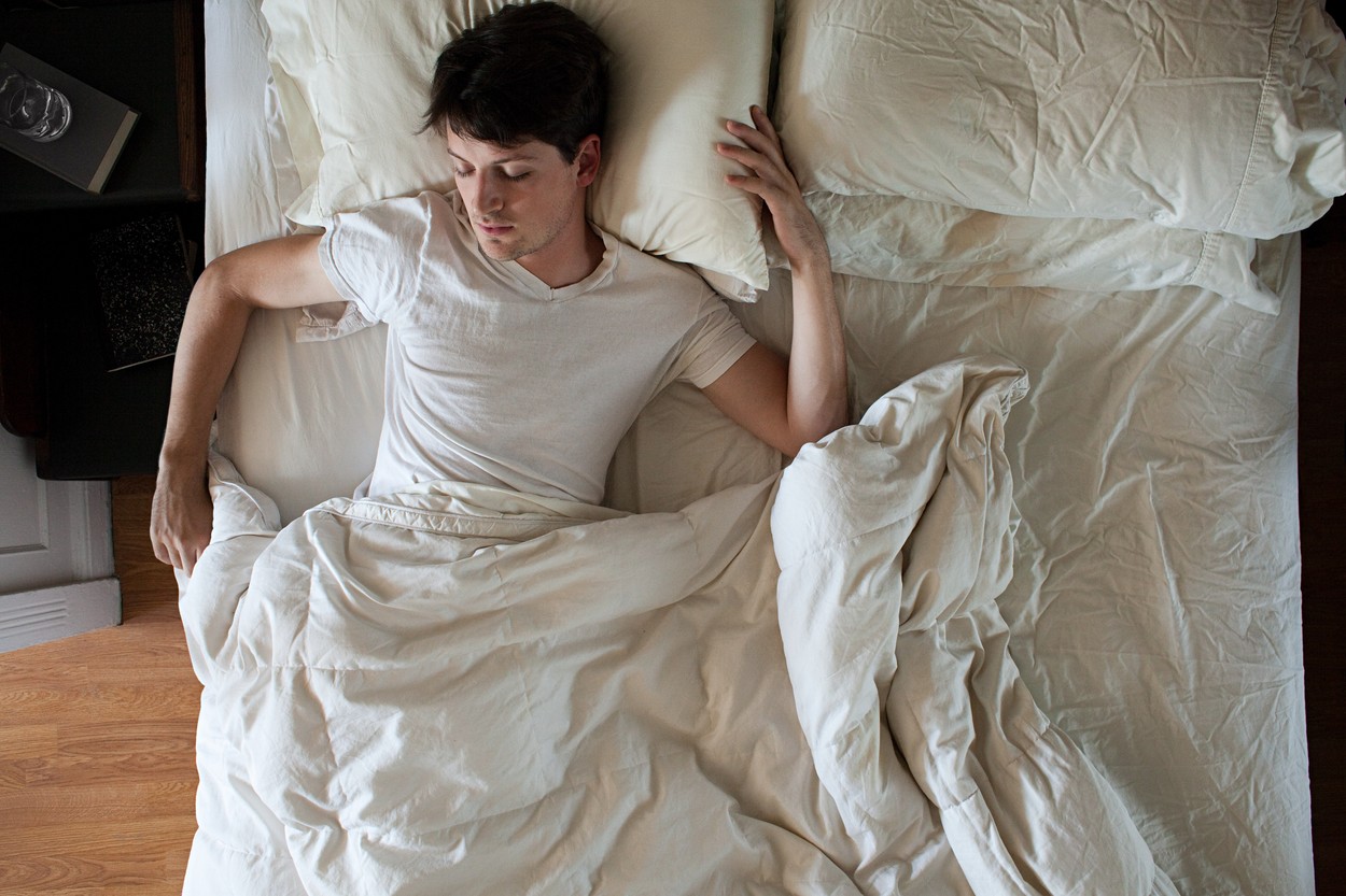 Man sleeping alone in double bed