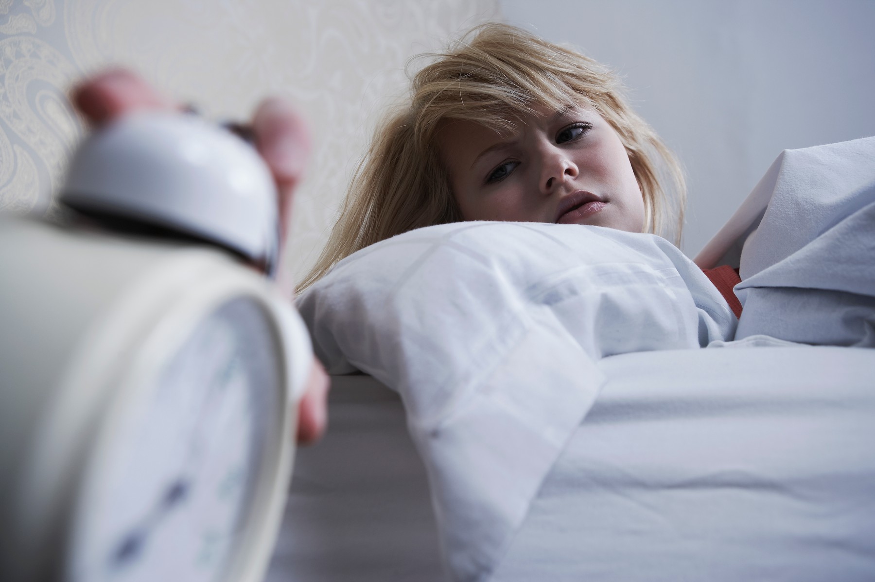 Teenage girl turning off alarm clock