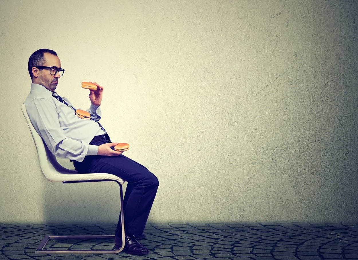 Business man feeling tired and sleepy after eating too many burgers for lunch
