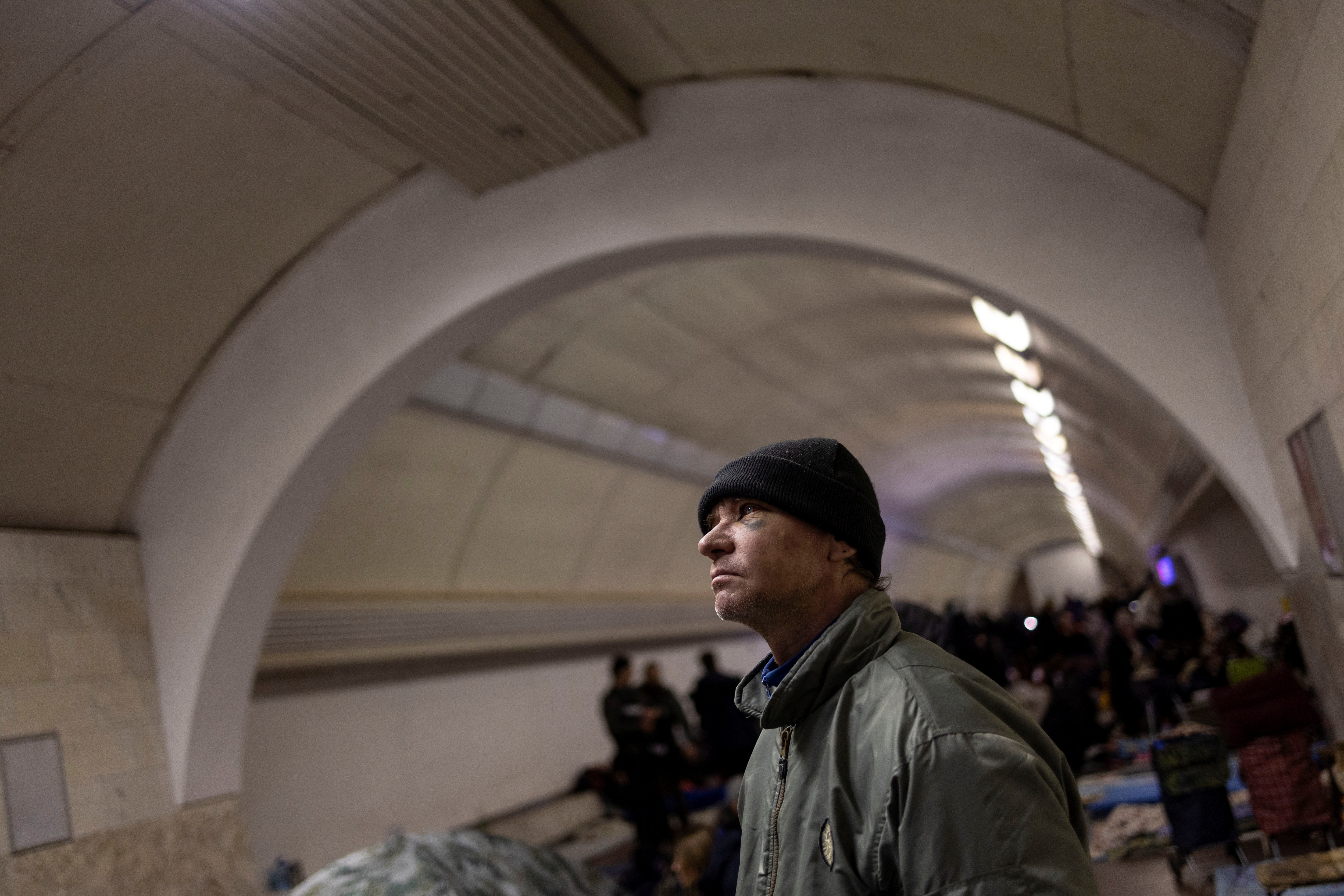 A man watches the local news as he takes shelter at an underground metro station as Russia's invasion of Ukraine continues, in Kyiv
